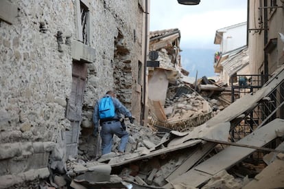 Un miembro del equipo de rescate busca entre los escombros en Amatrice.