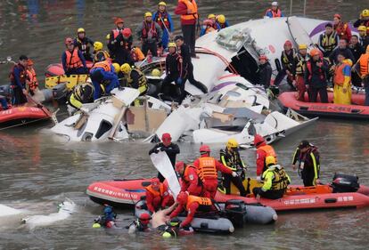 Vista del fuselaje del avión semisumergido en el río, mientras los equipos de rescate, subidos en balsas hinchables, intentan rescatar con cuerdas a ocupantes atrapados en el aparato.