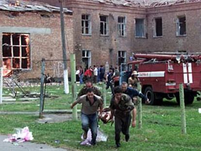 Un grupo de voluntarios saca a un herido de la escuela.