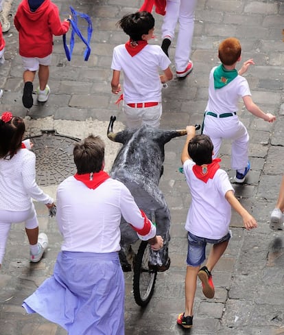 Niños corren junto a uno de los toros que protagonizan el 'encierro txiki' de los Sanfermines, Pamplona. 
