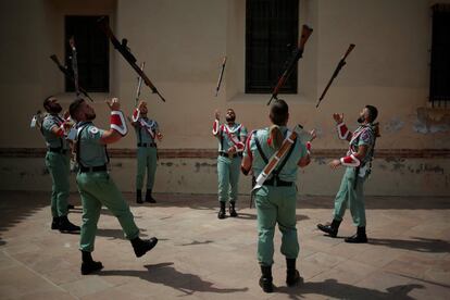 Varios legionarios lanzan sus armas en el aire mientras calientan antes de un cambio de guardia de honor en la imagen del Cristo de Mena, en Málaga, el 10 de abril de 2017.