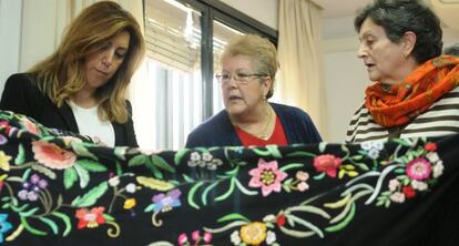 Díaz mira el trabajo de bordado de dos mujeres en un centro de día.