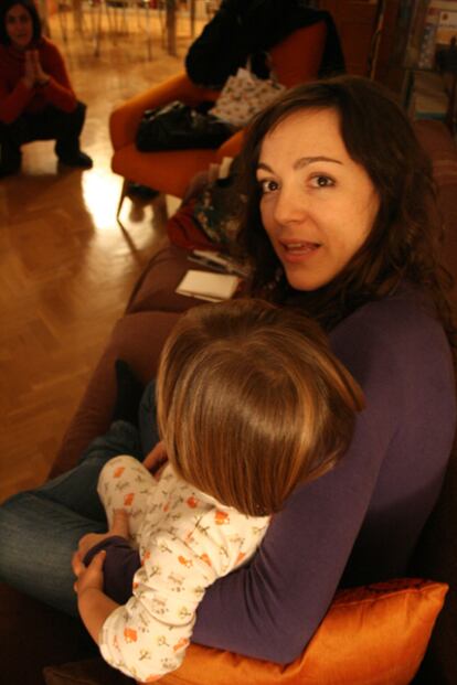 María Orcazarán, trabajadora de la asociación Progestión, sostiene en brazos a la hija de su amiga María Zapata (al fondo) que es voluntaria online en la misma entidad.
