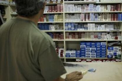 Una persona compra una cajetilla en un estanco.