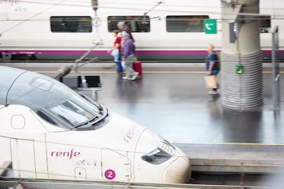 Viajeros con maletas entre trenes de Renfe en uno de los andenes de la estación madrileña de Atocha.