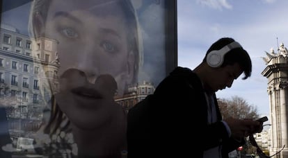 Un joven consulta su móvil junto a la Puerta de Alcalá, en Madrid.