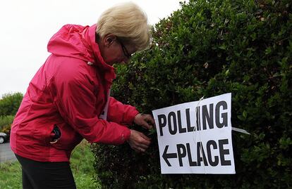 Los 50.000 centros de votación han abierto sus puertas sin incidentes a las siete de la mañana hora local (ocho en la España peninsular) en una jornada que se prolongará hasta las diez de la noche (una hora más). En la imagen, una mujer cuelga un cartel indicativo para que los votantes no se pierdan en North Queensferry, Escocia.