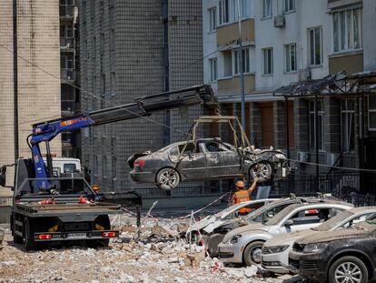 Trabajadores del Ayuntamiento de Kiev retiran varios coches destrozados por los ataques con drones sufridos por la capital de Ucrania la madrugada de este martes.