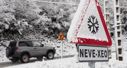 Un automóvil circula por una carretera nevada de Galicia.