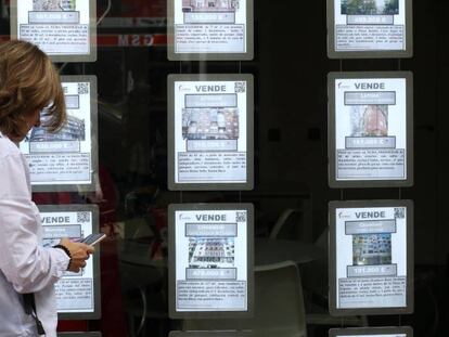 Una mujer delante del escaparate de una inmobiliaria en Madrid, en una imagen de archivo.