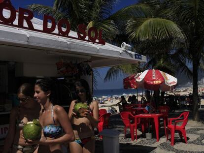 Banhistas tomam coco no calçadão da praia de Ipanema.