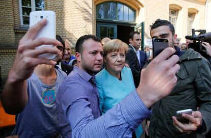 Un grupo de migrantes llegados de Siria e Irak se fotografía junto a Angela Merkel en las afueras de un campo de refugiados junto a la Oficina federal de Migración, el 10 de septiembre de 2015.
