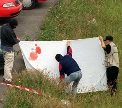 Agentes de la Ertzaintza cubren el cadáver de Santiago Oleaga en el lugar del atentado.