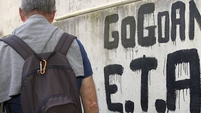 Un home camina al costat d'una pintada que resa "ETA, País Basc i Llibertat".