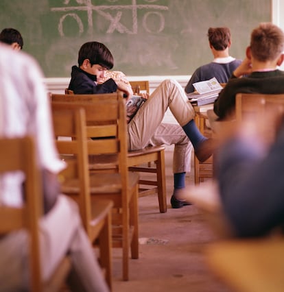 Un adolescente leyendo en un aula.