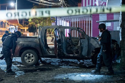 Policías inspeccionan un auto que explotó afuera de una oficina gubernamental en Quito (Ecuador), en agosto.