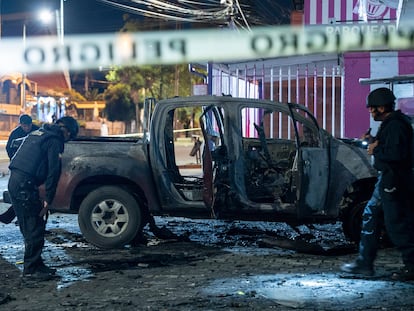 Policías inspeccionan un auto que explotó afuera de una oficina gubernamental en Quito (Ecuador), en agosto.