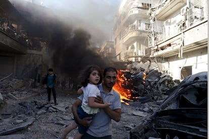 Um homem carregando uma criança afasta-se de local que, segundo ativistas, foi atacado pelas forças de Bashar al-Assad no bairro de Duma, em Damasco.