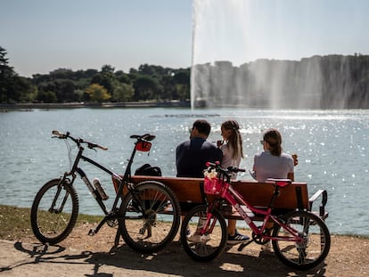 Una familia descansa en un banco en el Lago de Casa de Campo.