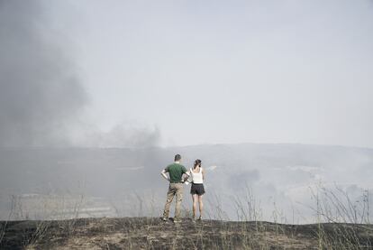 La sequía, las altas temperaturas y el viento que azotaba la zona se han conjurado para hacer crecer monstruosamente unas llamas que en solo seis horas han afectado mil hectáreas. En la foto, dos personas observan el incendio desde Manresa, este lunes.