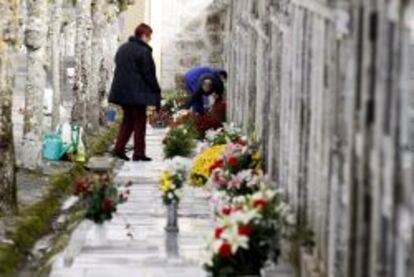 Varias personas limpian y adornan con flores hoy las tumbas de sus familiares en el cementerio de San Froil&aacute;n (Lugo).