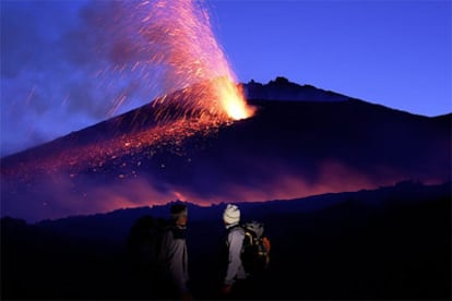 Dos turistas observan la lava que desprende el volcán Etna, situado en la isla italiana de Sicilia.