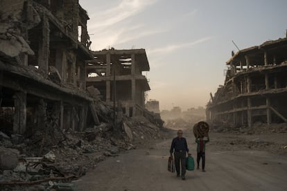 Haider (i) y Abdullah (d) llevan las pertenencias que han podido rescatar de los escombros de su casa para lavarlas antes de volver a instalarse en la Ciudad Vieja de Mosul.
