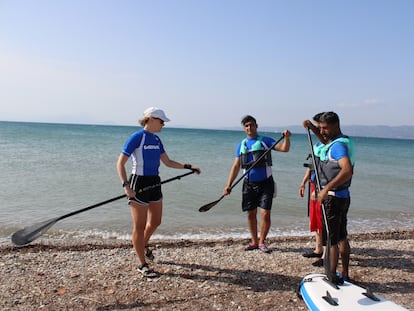 La instructora (izquierda) explica a los tres refugiados cómo manejar el pádel, en la playa de Skala Oropou, al norte de Atenas.