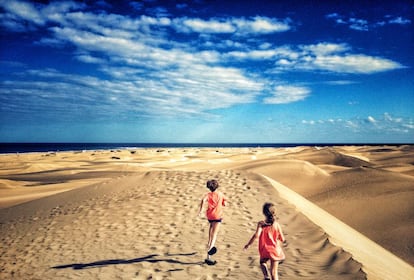 Dos niños corren en las dunas de Maspalomas, en la isla de Gran Canaria.