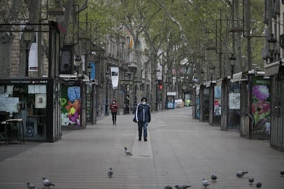 Dos personas con mascarilla caminan por la Rambla de Sant Josep el 25 de marzo en una desierta ciudad de Barcelona.