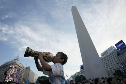 Un joven fanático besa una réplica del trofeo que recibe el ganador del mundial, durante los festejos en el centro de Buenos Aires.