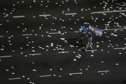 Seguidores de Mauricio Macri caminan con banderas argentinas por una calle llena de folletos en el centro de Buenos Aires.