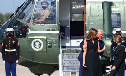 El presidente de los Estados Unidos, Donald Trump (sin mascarilla), abraza a la primera dama, Melania Trump, al bajar del helicóptero Marine One.