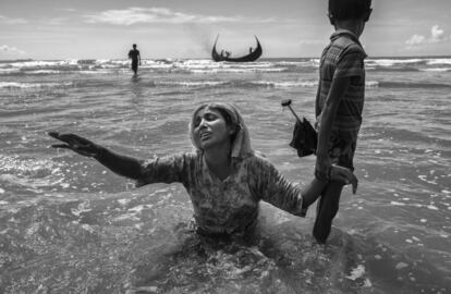 Una mujer refugiada Rohingya, derrumbada por el cansancio, busca a familiares después de llegar en barco a la orilla bangladesí del río Naf, en Shah Porir Dwip.