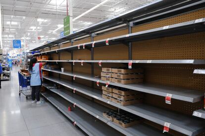 Una mujer trabaja limpia estantes de alimentos vacíos en un supermercado antes de la llegada del huracán 'Beryl', en Cancún.