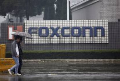 Una pareja camina junto a un complejo empresarial de Foxconn, en China. EFE/Archivo