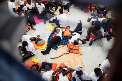 Un grupo de los migrantes rescatados duerme y descansa en la cubierta de la embarcación.