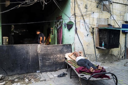 Un anciano duerme en una cama en una calle frente a su casa en Nueva Delhi (India).