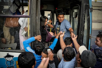 Unos pasajeros intentan subir a un bus durante una manifestación de transportistas, este jueves en Lima