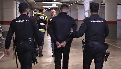 Agentes de la Policía Nacional trasladan a un detenido acusado de fraude.
