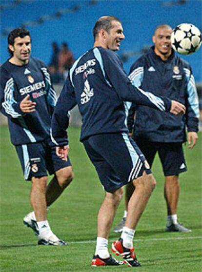 Zidane domina el balón, anoche, en la sesión preparatoria del Madrid, junto a Figo y Ronaldo.