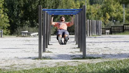 Un joven hace ejercicio en un gimnasio callejero en el Parque Central de Tres Cantos (Madrid).