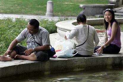 Varias personas se refrescan en una fuente de Madrid.