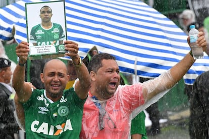 Un hombre porta la fotografía de una de las víctimas del accidente aéreo en el estadio de Chapeco (Brasil).