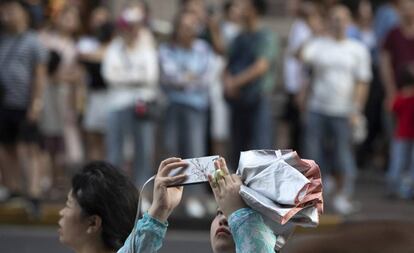 Una mujer toma una foto al Peace Hotel mientras un grupo espera la llegada de la delegación estadounidense en el diálogo comercial, este martes en Shanghái.