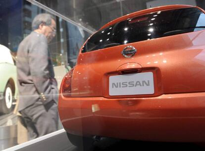 Un hombre mira un coche en el escaparate de un concesionario Nissan.