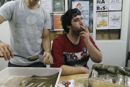 Dos socios de Pannagh en la sede de la asociación en Bilbao. Uno fuma marihuana, mientras el otro empaqueta bolsas de hachís que, posteriormente, prensa para una mejor conservación.