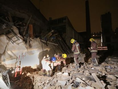 Cuatro agentes de los Bomberos de la Generalitat, ayer por la noche entre los escombros del edificio derrumbado en Sabadell.