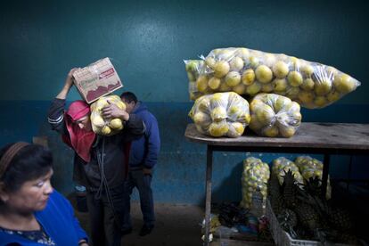 Cargadores ayudan a los compradores a llevar la fruta a sus coches.