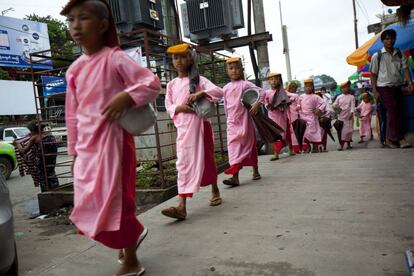 Pequeños monjes budistas caminan por una calle de Yangon para recoger arroz que les entregan los devotos y que constituye su único alimento el pasado 30 de junio.